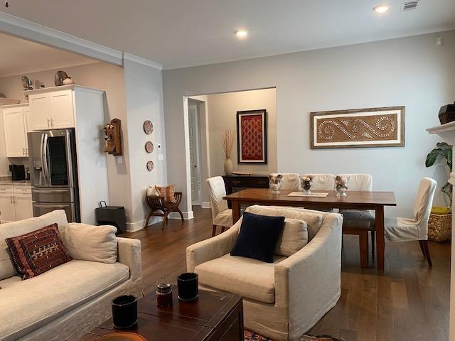 living area with visible vents, baseboards, recessed lighting, dark wood-type flooring, and crown molding