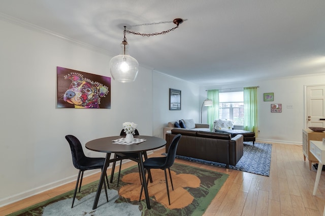 dining room with light wood finished floors, crown molding, and baseboards