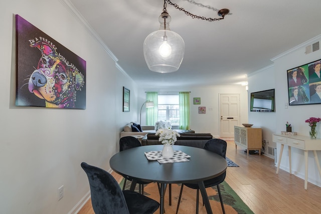 dining room featuring crown molding, baseboards, visible vents, and light wood-type flooring