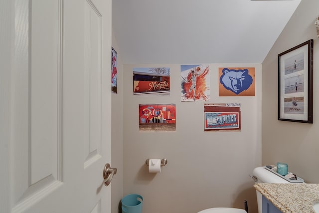 half bathroom featuring toilet, vanity, and lofted ceiling