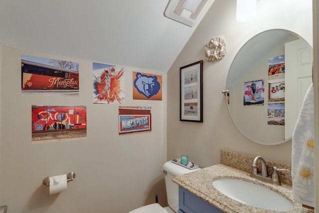 half bathroom with vanity, lofted ceiling, toilet, and visible vents