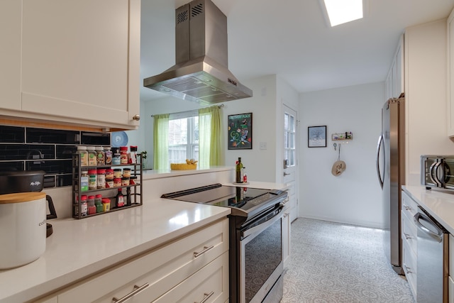 kitchen with island exhaust hood, stainless steel appliances, white cabinetry, and light countertops