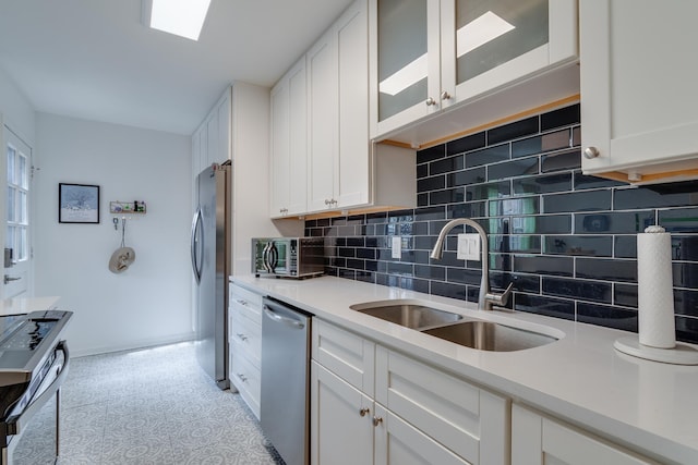 kitchen with a sink, stainless steel appliances, light countertops, and white cabinetry