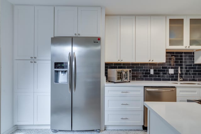 kitchen featuring decorative backsplash, white cabinets, and stainless steel appliances