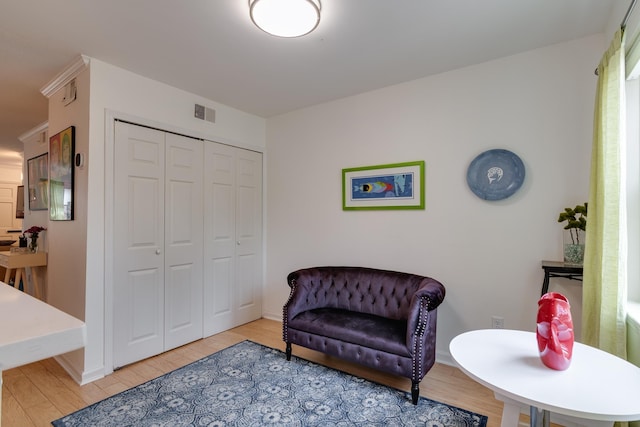 sitting room with visible vents, light wood-type flooring, and baseboards