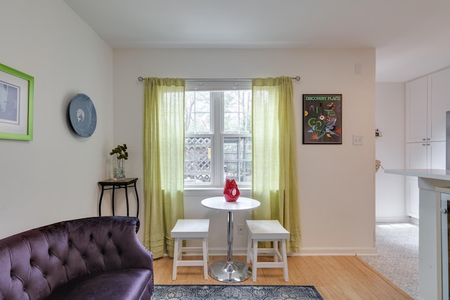 living area with light wood-type flooring and baseboards