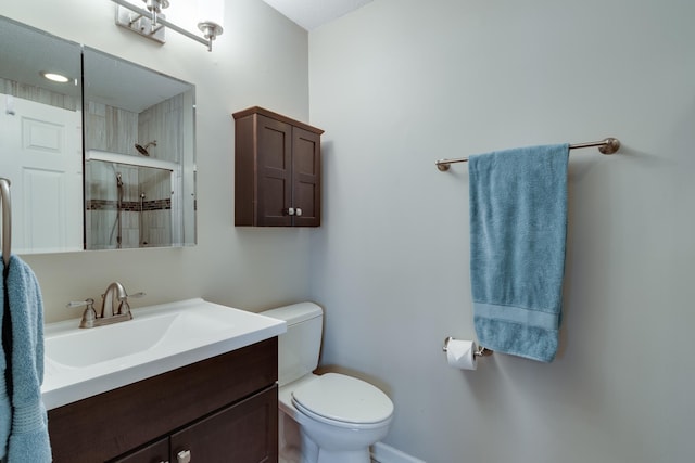 bathroom featuring toilet, a stall shower, and vanity