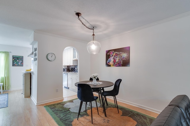 dining area with ornamental molding, baseboards, arched walkways, and light wood-type flooring