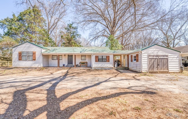 ranch-style home featuring driveway, a porch, fence, an outdoor structure, and metal roof
