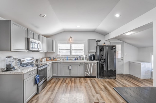 kitchen with vaulted ceiling, appliances with stainless steel finishes, and gray cabinetry