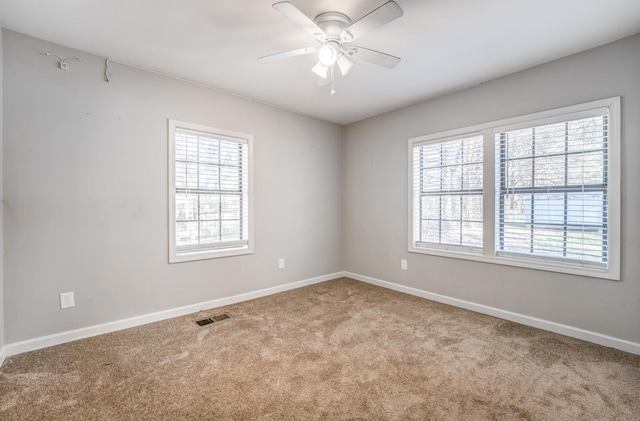 carpeted empty room featuring visible vents, plenty of natural light, baseboards, and ceiling fan