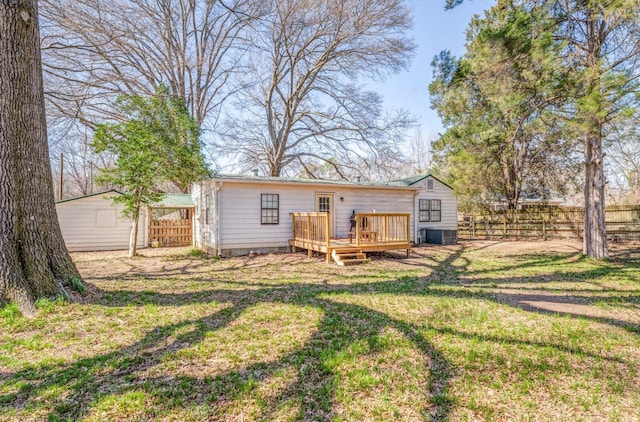 rear view of house with an outbuilding, fence, a wooden deck, a yard, and central AC