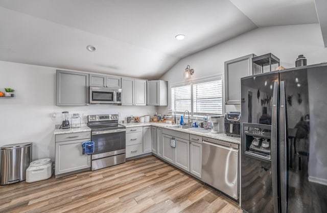 kitchen with gray cabinetry, stainless steel appliances, and lofted ceiling