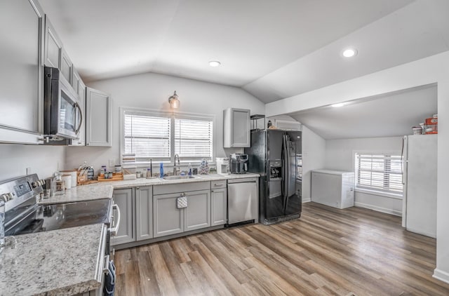 kitchen with vaulted ceiling, gray cabinetry, stainless steel appliances, and a sink