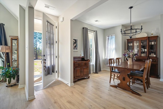 dining area featuring light wood-type flooring, visible vents, a notable chandelier, and a healthy amount of sunlight