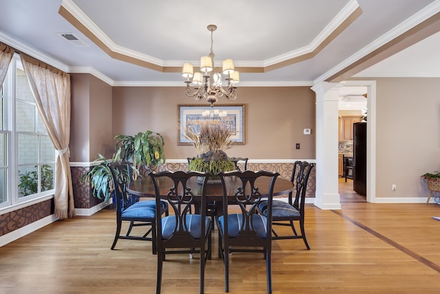 dining room featuring a tray ceiling, a notable chandelier, visible vents, and light wood-style flooring