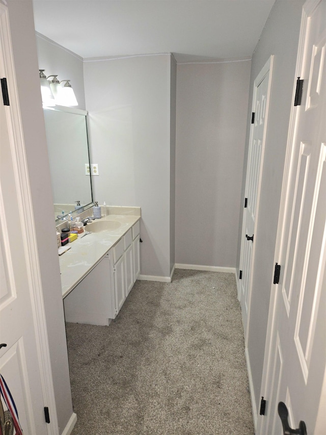 bathroom featuring vanity, baseboards, and carpet floors