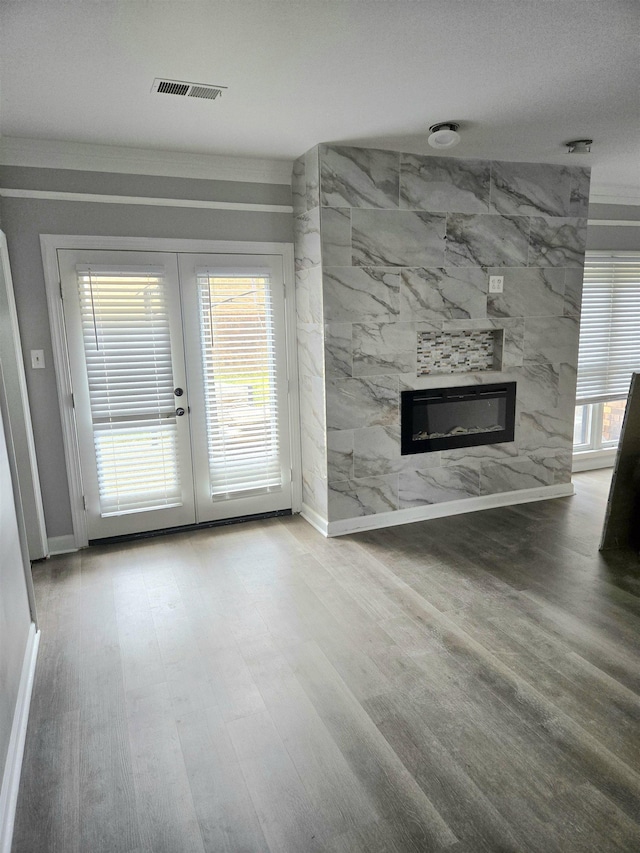 unfurnished living room with baseboards, french doors, wood finished floors, and a premium fireplace