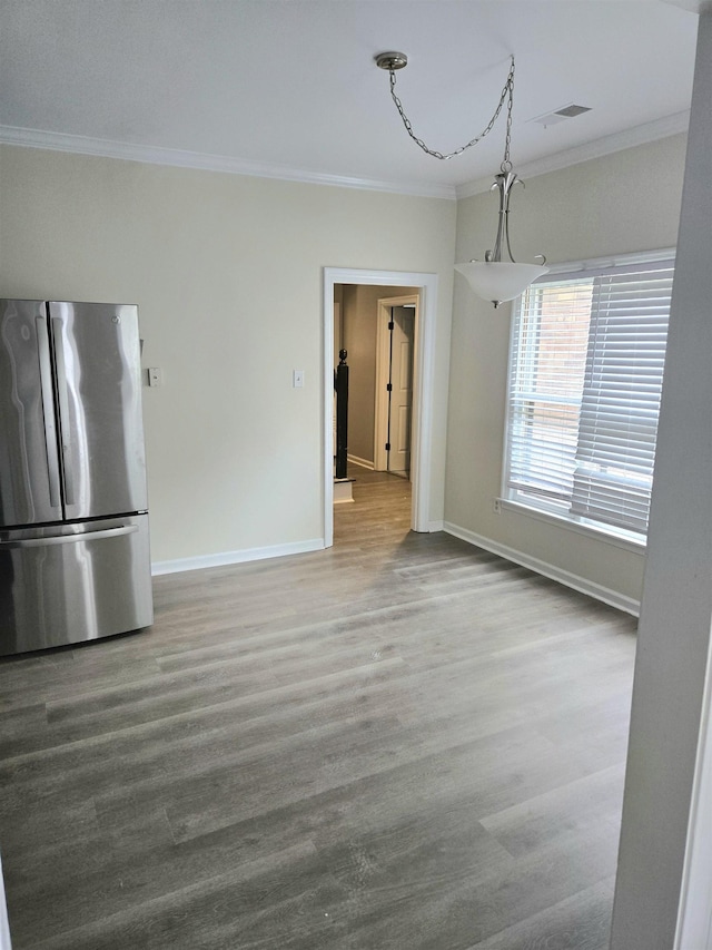 unfurnished dining area with baseboards, ornamental molding, wood finished floors, and visible vents