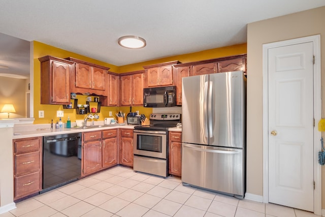 9995 Woodland Birch Dr, Lakeland, TN 38002 - kitchen with light tile patterned floors, brown cabinetry, a sink, black appliances, and light countertops