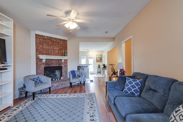 9995 Woodland Birch Dr, Lakeland, TN 38002 - living area featuring a brick fireplace, a textured ceiling, a ceiling fan, and wood finished floors