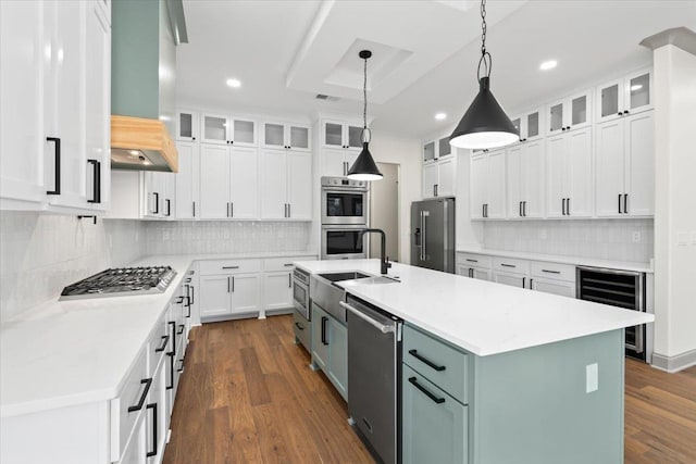 kitchen with white cabinets, wine cooler, dark wood-style floors, a center island with sink, and appliances with stainless steel finishes