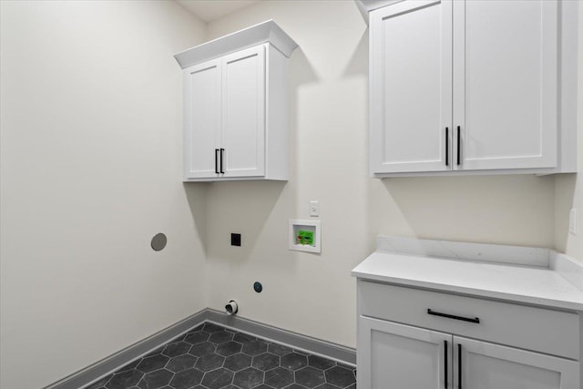laundry room featuring hookup for a washing machine, baseboards, dark tile patterned flooring, electric dryer hookup, and cabinet space
