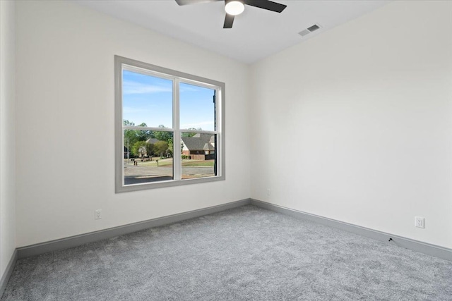 carpeted spare room featuring baseboards, a ceiling fan, and visible vents