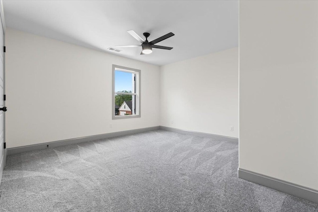 carpeted spare room featuring baseboards, a ceiling fan, and visible vents