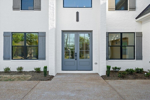 view of exterior entry featuring french doors and brick siding