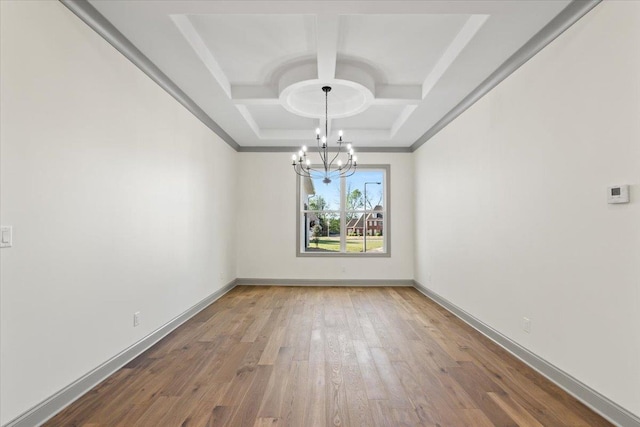 unfurnished dining area with coffered ceiling, a notable chandelier, wood finished floors, and baseboards