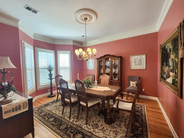 dining space with visible vents, a notable chandelier, light wood-style flooring, and crown molding