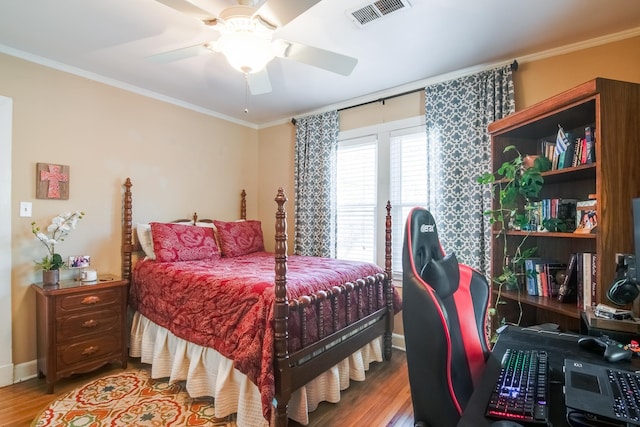 bedroom featuring visible vents, ornamental molding, a ceiling fan, wood finished floors, and baseboards