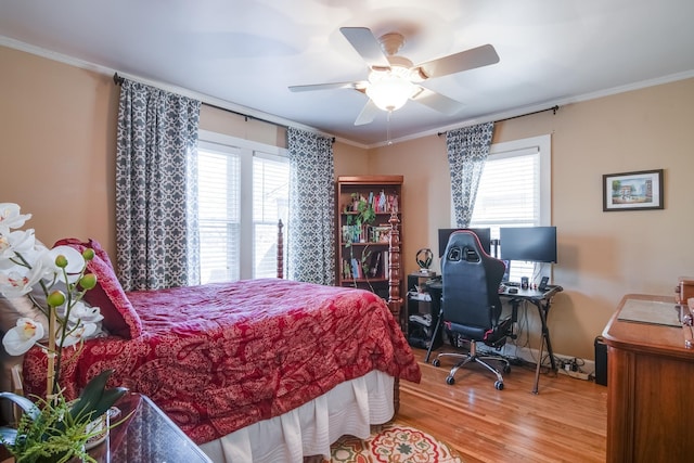 bedroom with multiple windows, wood finished floors, a ceiling fan, and ornamental molding