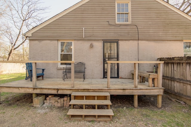 back of property featuring a wooden deck, brick siding, and fence