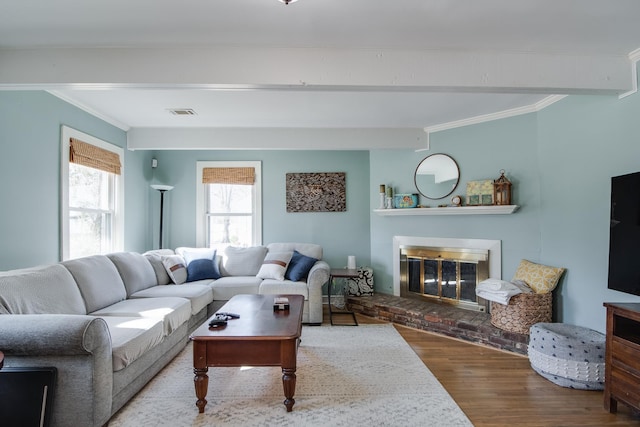living area with visible vents, a brick fireplace, wood finished floors, and crown molding