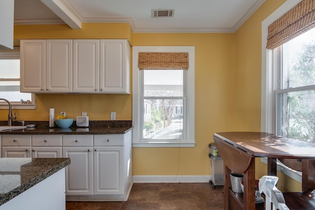 kitchen with visible vents, white cabinetry, and crown molding