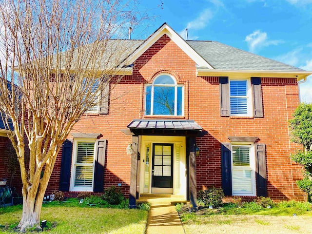 view of front of house with brick siding, a front lawn, and a shingled roof