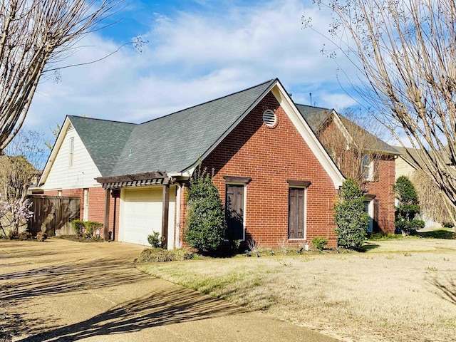 view of front of home with a front yard, roof with shingles, an attached garage, concrete driveway, and brick siding