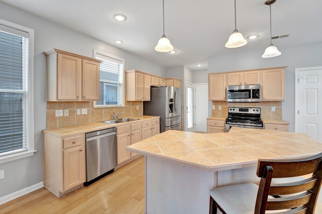 kitchen with light wood-type flooring, visible vents, light brown cabinetry, a sink, and appliances with stainless steel finishes