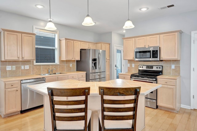 kitchen featuring appliances with stainless steel finishes, tile counters, and light brown cabinetry