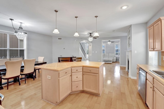 kitchen with tile countertops, light wood-style flooring, light brown cabinetry, stainless steel dishwasher, and ceiling fan with notable chandelier