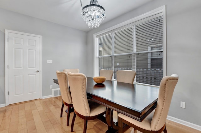 dining area with light wood-style floors, baseboards, a notable chandelier, and visible vents