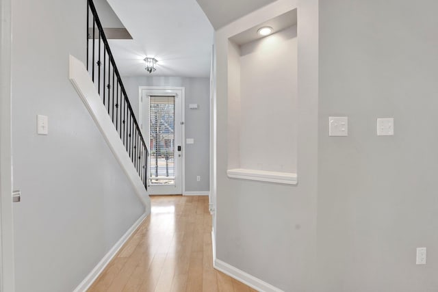 entrance foyer with stairway, baseboards, and light wood finished floors