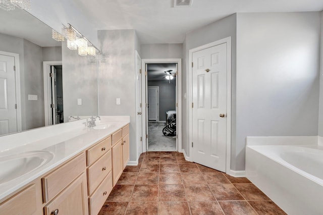 full bath with visible vents, a garden tub, a sink, double vanity, and baseboards