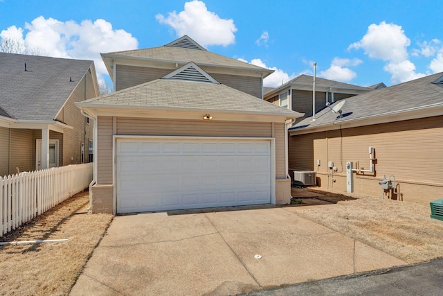 garage with cooling unit, concrete driveway, and fence