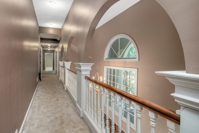 7570 Chapel Ridge Dr, Memphis, TN 38016 - hall with arched walkways, an upstairs landing, light colored carpet, and baseboards