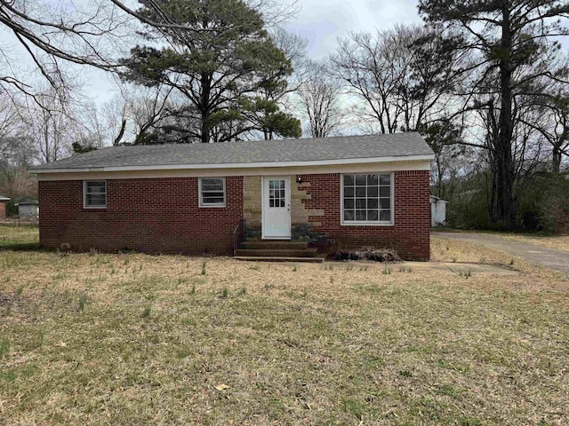 single story home featuring brick siding, a shingled roof, a front lawn, and entry steps