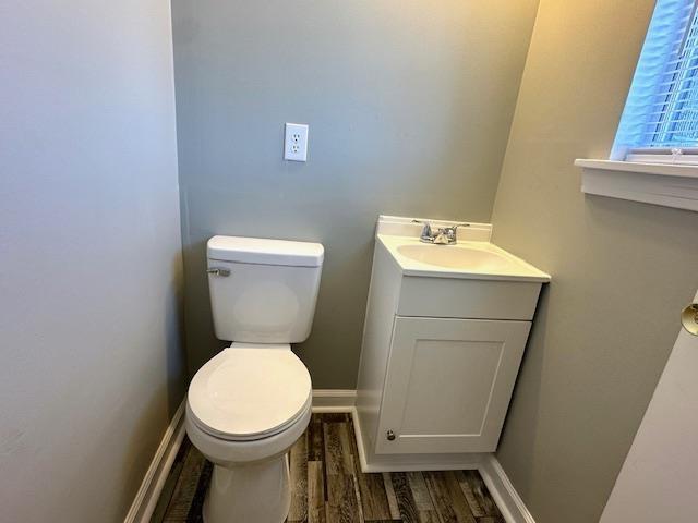 bathroom with baseboards, toilet, wood finished floors, and vanity