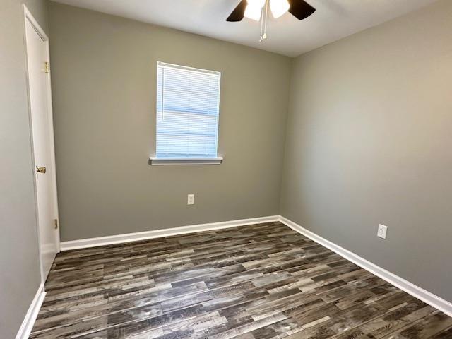 spare room featuring dark wood finished floors, baseboards, and ceiling fan